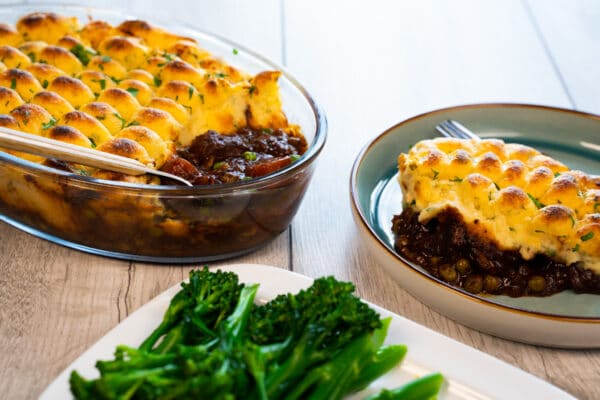 Cooking dish with shepherd's pie next to plated dish and side of tenderstem brocolli