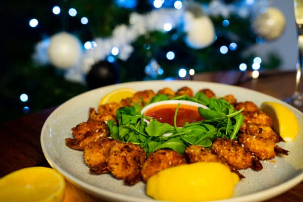 Plate of salt and pepper prawns in front of Christmas tree