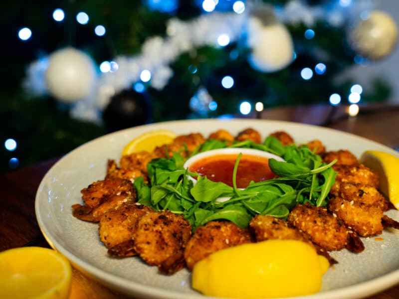 Plate of salt and pepper prawns in front of Christmas tree