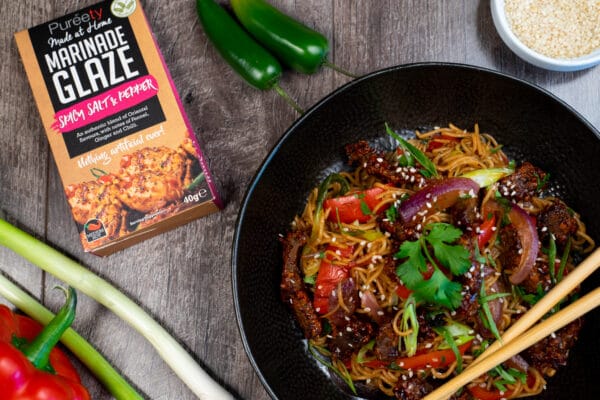 Top down image of chilli beef noodles with garnish and pack