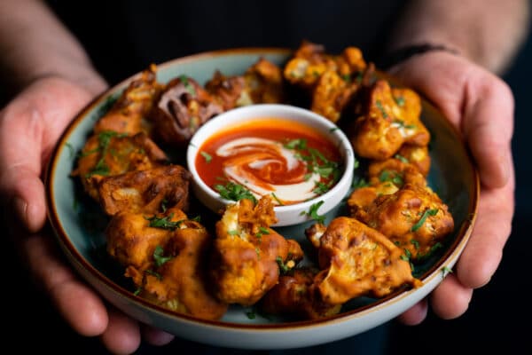 Chef holding plate of cauliflower wings and dip